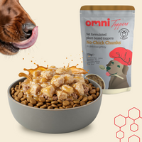 Dog eating from a bowl of food with Omni Toppers packaging in the background